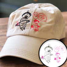 Load image into Gallery viewer, khaki baseball hat with two stick figure drawings of characters with hearts inside of speech bubbles