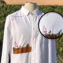 Load image into Gallery viewer, white button up shirt with custom embroidery of drawing of red house on brown field
