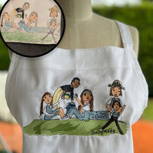 Load image into Gallery viewer, white apron with custom embroidery of drawing of family of five on a picnic