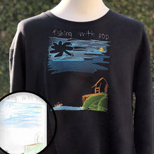 Load image into Gallery viewer, custom embroidery of a childrens drawing on a crew neck pullover black sweatshirt.  drawing is of a stick figure family on a brown boat on a blue sea next to a neon green hill with a brown hut.  overhead there is an embroidered sky in shades of blue with a large cloud