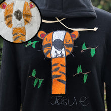 Load image into Gallery viewer, black hoodie with custom embroidery of orange happy tiger and artist signature "josue" under a collection of green leaves