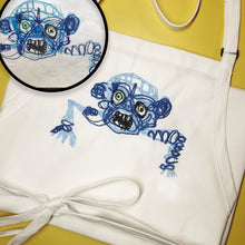Load image into Gallery viewer, white chefs apron with custom embroidery of kids drawing of swirly blue  evil zombie monster